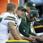 Green Bay Packers quarterback Aaron Rodgers, second from left, looks toward the scoreboard as he sits on the bench during the first half of an NFL football game against the Seattle Seahawks, Thursday, Sept. 4, 2014, in Seattle. (AP Photo/Stephen Brashear)