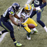 Seattle Seahawks' Earl Thomas, left, muffs the catch on a punt as Green Bay Packers' Davon House reaches for the ball in the first half of an NFL football game, Thursday, Sept. 4, 2014, in Seattle. The Seahawks got possession. (AP Photo/Scott Eklund)