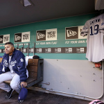 San Diego Padres' Alex Torres, left, and coach Jose Valentine sit near a jersey hanging in the team's dugout honoring Tony Gwynn before a baseball game against the Seattle Mariners Monday, June 16, 2014, in Seattle. It was announced earlier Monday that Gwynn, who had more than 3,100 hits during a career spanning two decades, died at age 54 following a battle with oral cancer. (AP Photo/Elaine Thompson)