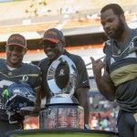 Seattle Seahawks quarterback Russell Wilson, of Team Irvin, left, Michael Irvin, Pro Bowl legend team captain and Pro Football Hall of Famer, center, and Seattle Seahawks defensive end Michael Bennett, of Team Irvin, right, stand with the winning trophy after the NFL Pro Bowl football game Sunday, Jan. 31, 2016, in Honolulu. Bennett won the defensive MVP and Wilson won the offensive MVP award. Team Irving beat Team Rice 49-27. (AP Photo/Marco Garcia)