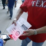 Customer Service Representative Bea Finley, left, scans Jerry Whitehead's ticket before the Opening Day baseball game between the Seattle Mariners and Texas Rangers, Monday, April 4, 2016, in Arlington, Texas. (AP Photo/Brandon Wade)