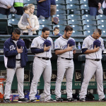 San Diego Padres players stand during a moment of silence in honor of Tony Gwynn before a baseball game against the Seattle Mariners Monday, June 16, 2014, in Seattle. It was announced earlier Monday that Gwynn, who had more than 3,100 hits during a career spanning two decades, died at age 54 following a battle with oral cancer. (AP Photo/Elaine Thompson)